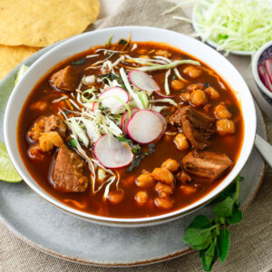 This pozole rojo is full of deep flavor with pork, chiles and garnished with shredded cabbage and sliced radish.