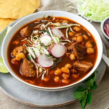 This pozole rojo is full of deep flavor with pork, chiles and garnished with shredded cabbage and sliced radish.