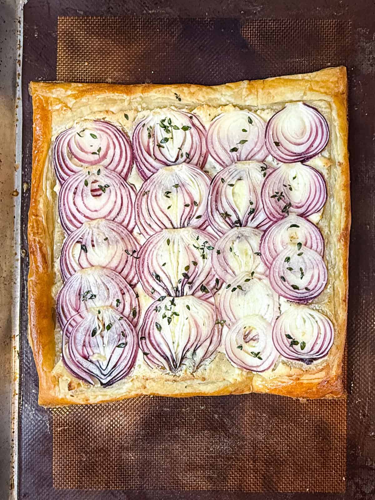 Bake the onion cheese tart until the puff pastry is golden brown and onions are slightly caramelized.
