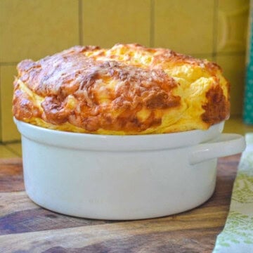 Tall, fluffy cheese souffle with a beautifully puffed, golden-brown top.